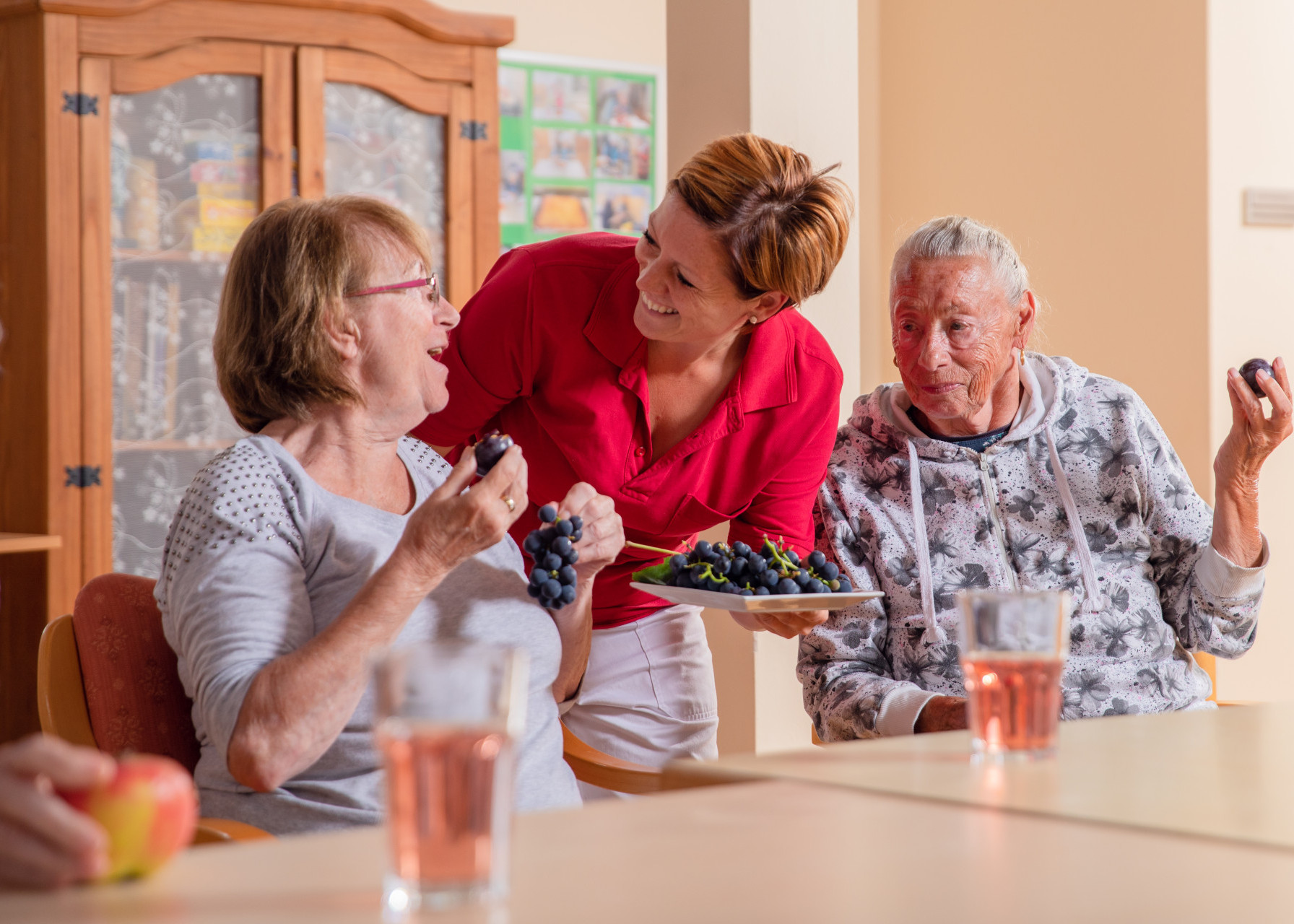 Betreuerin unterhält sich mit zwei Bewohnerinnen bei einer gemeinsamen Obst-Jause.